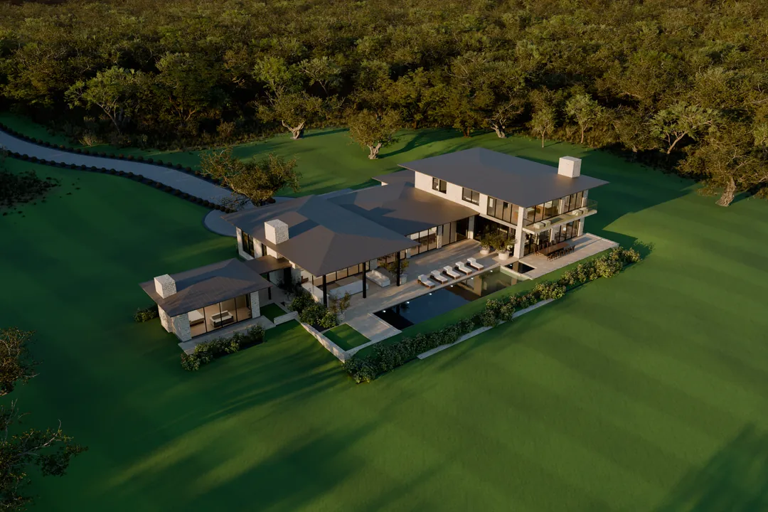 Aerial view at golden hour of the L-shaped house, terrace and pool on a striped lawn, with the curving drive and oak woodland behind.